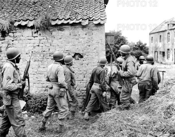 Platoon of black American troops surrounding French farm house as they prepare to eliminate German sniper holding up an advance, Omaha Beachhead, near Vierville-sur-Mer, France, U.S. Army Signal Corps, June 10, 1944