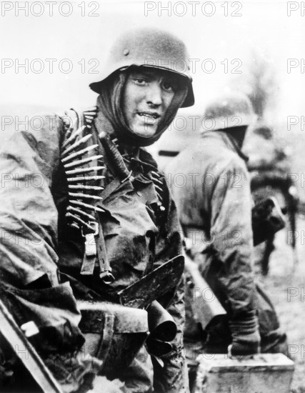 Nazi soldier, heavily armed, carrying ammunition boxes forward with companion in territory taken by their counter-offensive, Belgium, German film captured by the U.S. Army Signal Corps, December 1944