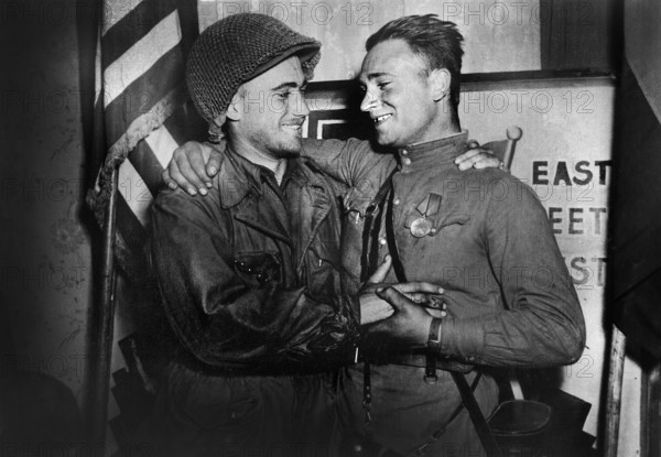U.S. 2nd Lieutenant William Robertson and Lt. Alexander Sylvashko, Russian Army, in front of sign "East Meets West" symbolizing historic meeting of Russian and American Armies, near Torgau, Germany,