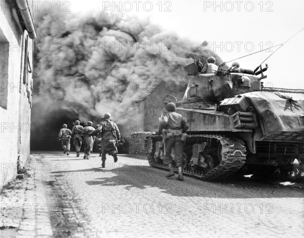 U.S. soldiers of 55th Armored Infantry Battalion and tank of the 22nd Tank Battalion, moving through smoke filled street, Wernberg, Germany, U.S. Army Signal Corps, April 22, 1945