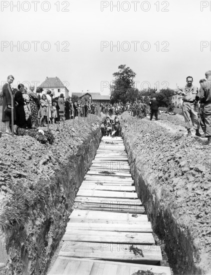 Civilians giving burial to 800 victims of SS killing. which was ordered by the military government after bodies were laying in open for five days, Nammering, Germany, U.S. Army Signal Corps, May 19, 1945