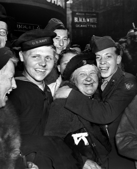 Jubilant American soldier hugging motherly English woman and victory smiles light the faces of happy service men and civilians at Piccadilly Circus, celebrating Germany's unconditional surrender, London, England, UK, U.S. Army Signal Corps, May 7, 1945