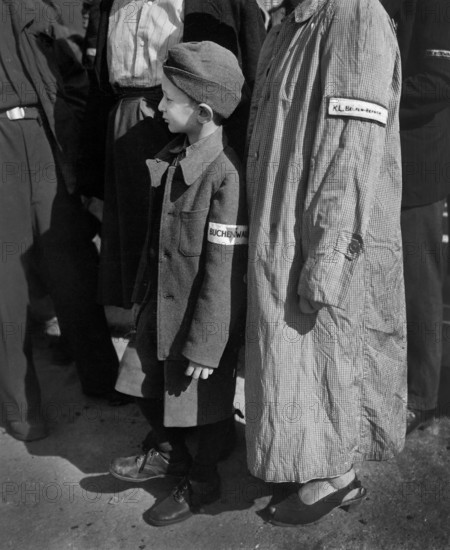 Six-year-old war orphan with Buchenwald badge on his sleeve waiting for his name to be called at roll call at Buchenwald camp, Germany, for departure to Switzerland, U.S. Army Signal Corps, June 19, 1945