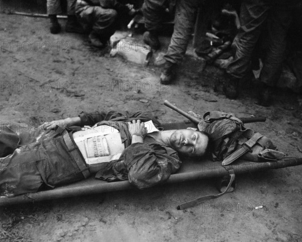 Private First Class, Thomas Conlon, 21st Infantry Regiment, laying on stretcher at medical aid station, after being wounded while crossing the Nakdong River, South Korea, U.S. Army Signal Corps, September 19, 1950