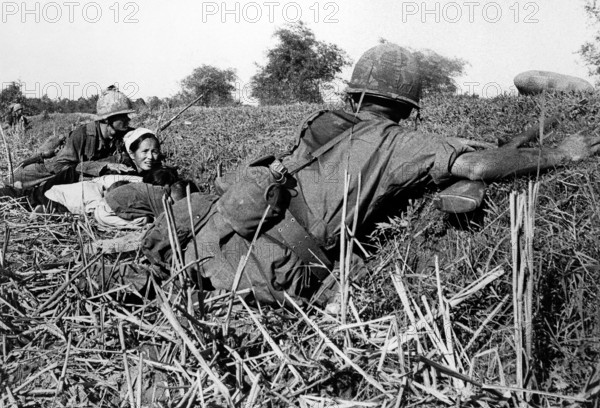 American soldier of 1st Infantry Division motioning to woman refugee to keep her children's heads down during battle, Vietnam, U.S. Army Signal Corps, January 16`, 1966