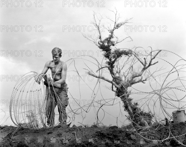 Member of 1st Brigade, 5th Infantry Division (Mechanized), taking down barbed tape (modified form of concertina wire) surrounding command post of Operation Utah Mesa, A Shau Valley, Vietnam, U.S. Army Signal Corps, July 1969
