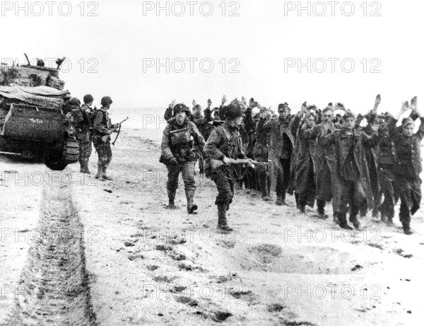 American soldiers marching group of German prisoners along beachhead after which they will be sent to England, Normandy, France, U.S. Army Signal Corps, June 6, 1944