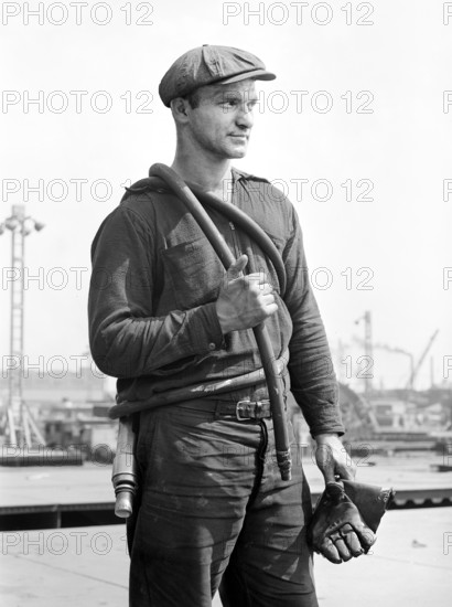 Factory worker carrying rubber hose, Bethlehem-Fairfield shipyards, Baltimore, Maryland, USA, Arthur S. Siegel, U.S. Office of War Information, May 1943