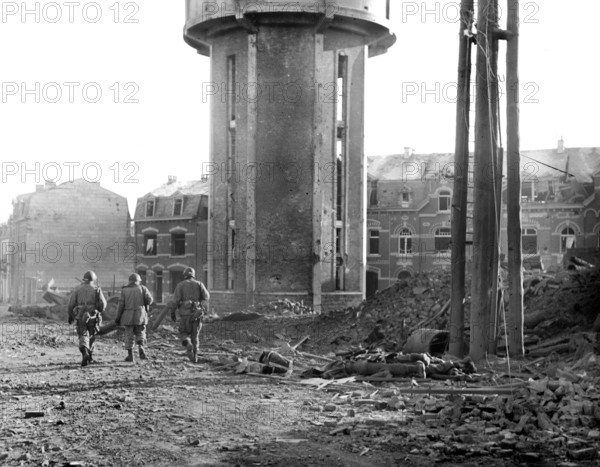 Members of U.S. 101st Airborne Division walking past dead comrades, killed during Christmas Eve bombing, Bastogne, Belgium, U.S. Army Signal Corps, December 25, 1944