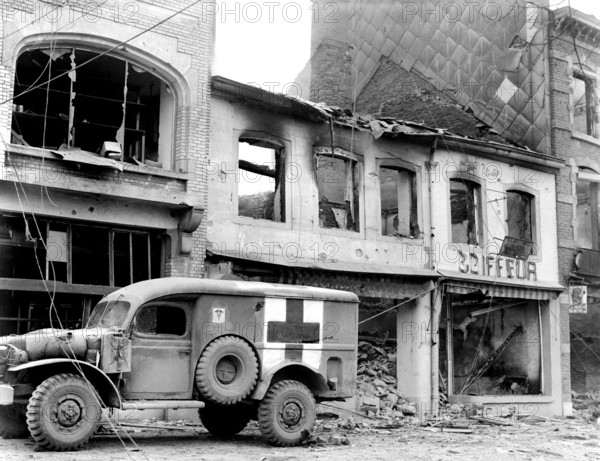 American ambulance waiting outside bombed building while a searcher looks for persons injured during ten-day defense by 101st Airborne Division, Bastogne, Belgium, U.S. Army Signal Corps, December 26, 1944