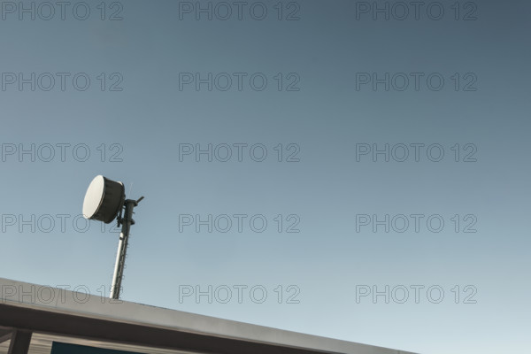 Microwave transmitter mounted to the roof against blue sky
