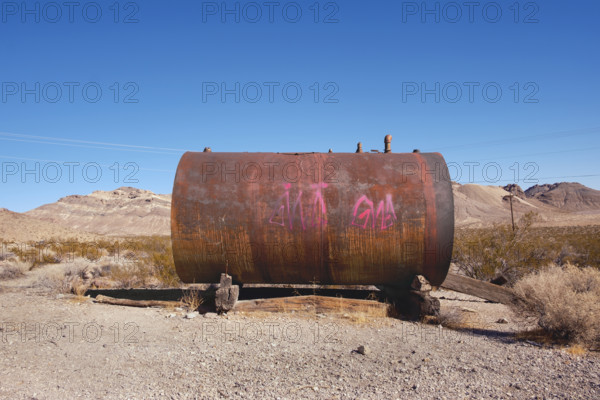 Rusted metal storage tank with painted graffiti in abandoned ghost town, Rhyolite, Nevada, USA