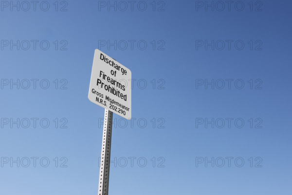 Discharge of Firearms Prohibited' warning sign, low angle view against blue skey,