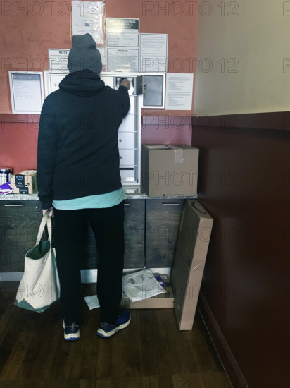 Rear view of man checking mailbox in apartment building lobby, Brooklyn, New York, USA