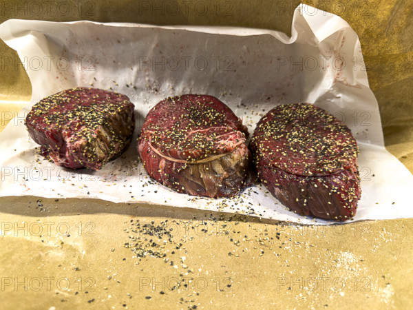 three cuts of raw filet mignon seasoned with herbs