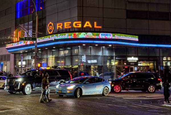 Regal movie theaters and street scene at night, New York City, New York, USA