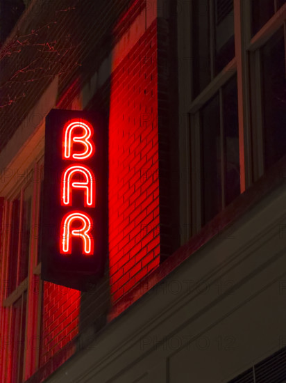Neon red bar sign on building exterior at night, New York City, New York, USA
