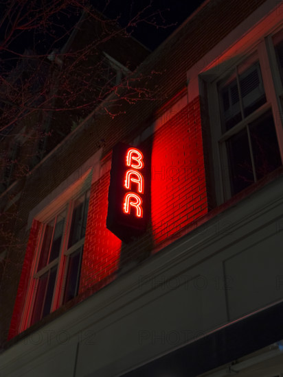 Neon red bar sign on building exterior at night, New York City, New York, USA