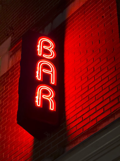 Neon red bar sign on building exterior at night, New York City, New York, USA