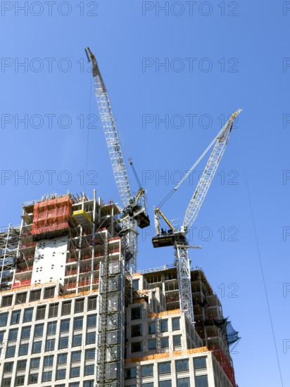 Construction cranes atop new residential building under construction, New York City, New York, USA
