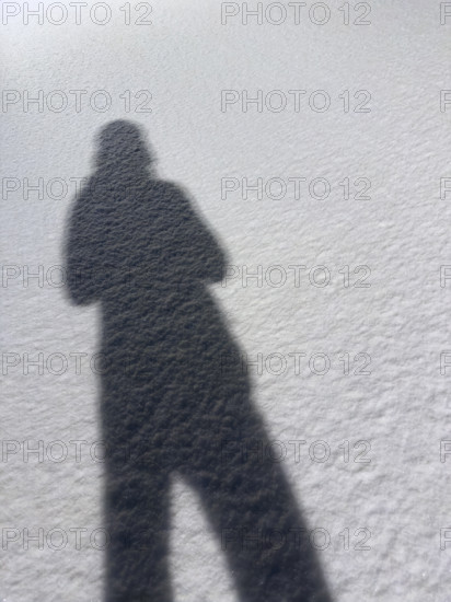 Shadow of person on snow-covered ground