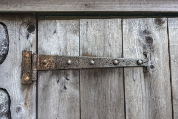 Rusted door hinge on weathered door