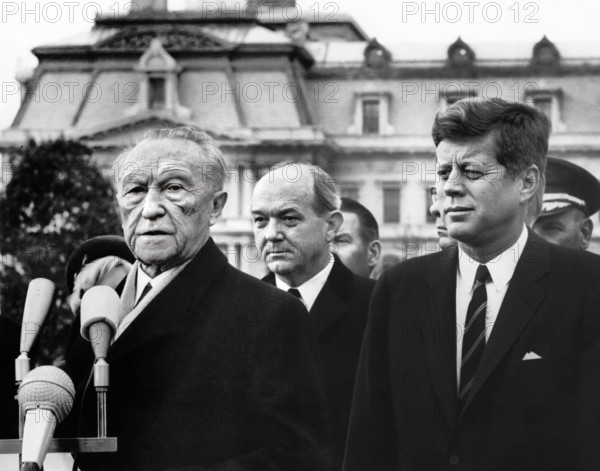 U.S. President John F. Kennedy looking on as Chancellor of West Germany, Dr. Konrad Adenauer, delivers remarks during arrival ceremonies in his honor with U.S. Secretary of State, Dean Rusk, standing in center, South Lawn, White House, Washington, D.C., USA, Abbie Rowe, White House Photographs, November 14, 1962