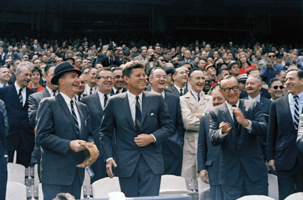 U.S. President John F. Kennedy (laughing), California Governor Edmund "Pat" Brown, (clapping, right), Minnesota Senator Hubert Humphrey (behind Kennedy's left shoulder) and others attending opening day of baseball season, at D.C. Stadium, Washington, D.C., USA, Robert Knudsen, White House Photographs, April 8, 1963