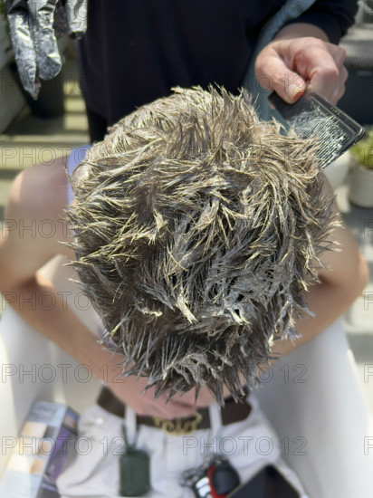 High angle view of young adult man getting his hair bleached
