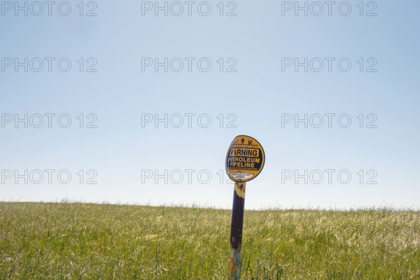 Buried petroleum pipeline warning sign in rural field