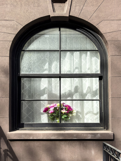 Flower arrangement on sill of residentail apartment's arched window, New York City