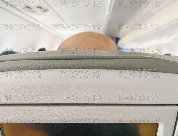 Top of man's bald head in airplane seat, rear view