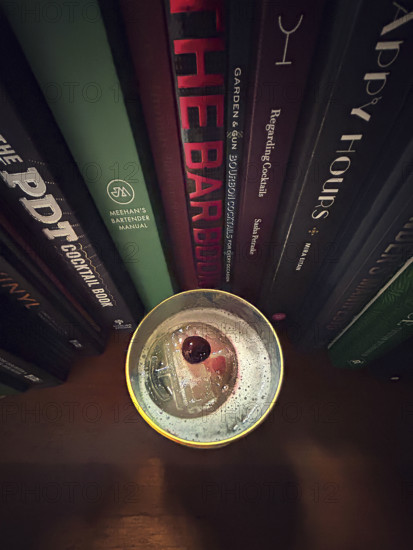 High angle view of whiskey sour cocktail against a row of cocktail recipe books