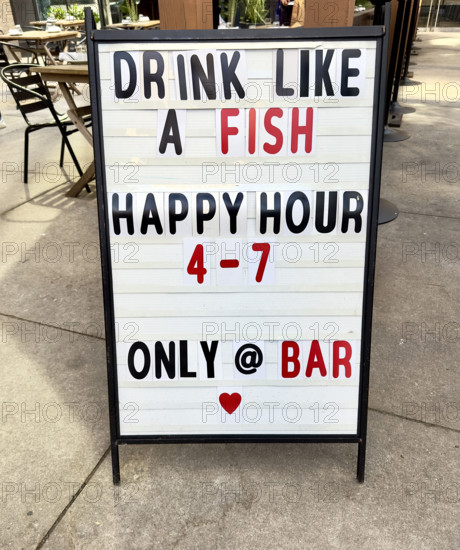 Happy hour sign on urban sidewalk, New York City