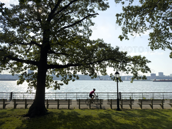 Bicyclist on westside bike path along Hudson River with view of New Jersey in background, Manhattan, New York City