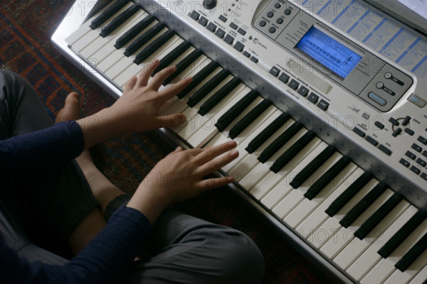 High angle view of young boy playing electric keyboard