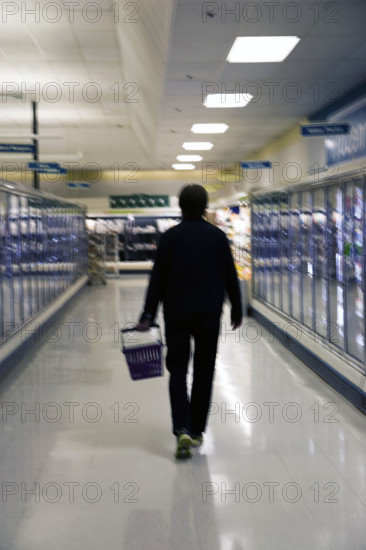 Rear view of mid-adult man shopping for groceries in supermarket