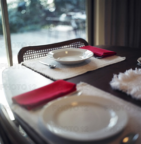 Two empty plates on a dinner table near sliding patio door