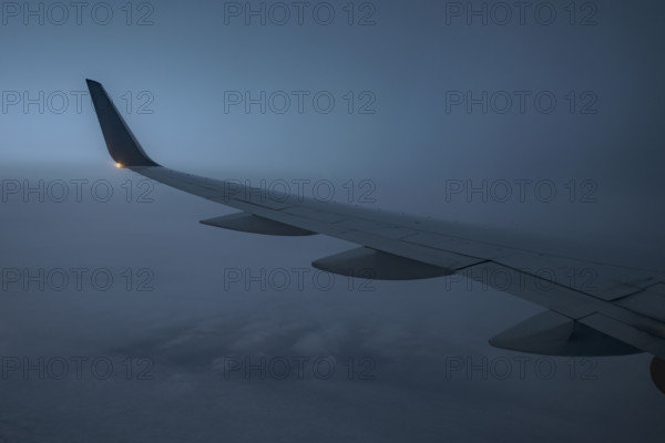 Commercial airplane wing viewed from passenger window at dusk