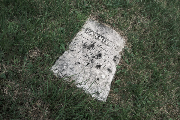 Old weathered gravestone laying on grass field