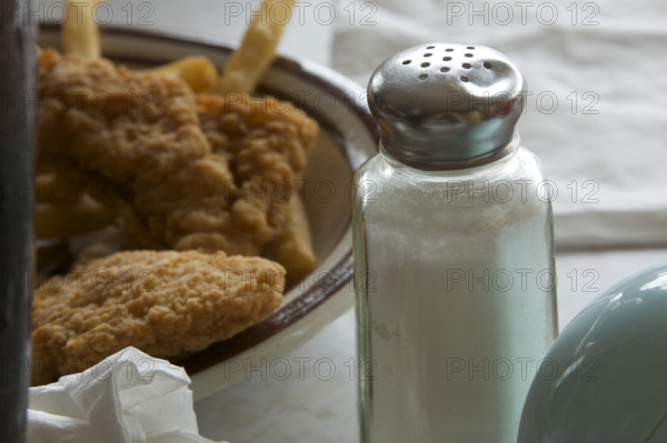 Plate of chicken tenders and french fries with a dented salt shaker