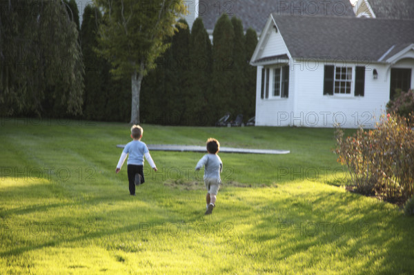 Rear view of two young boys running on a residential lawn