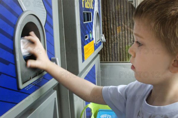 Young boy recycling cans in recycling bin
