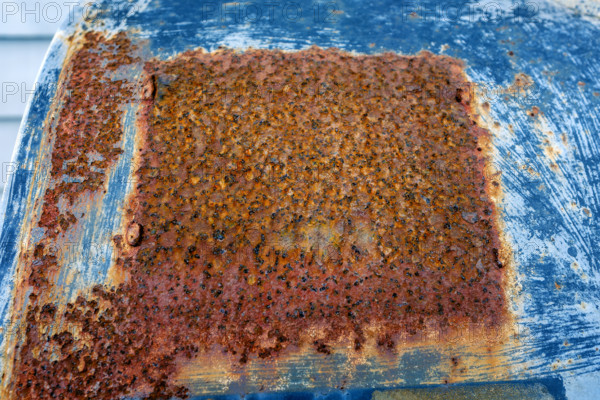 Large rust patch on blue painted oil tank
