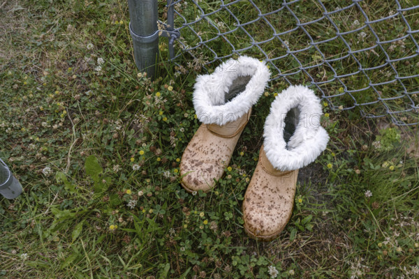 High angle view of two boots near chain link fence