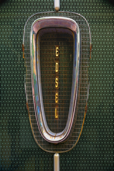 Antique rusted Ford Edsel car grille against green metal background