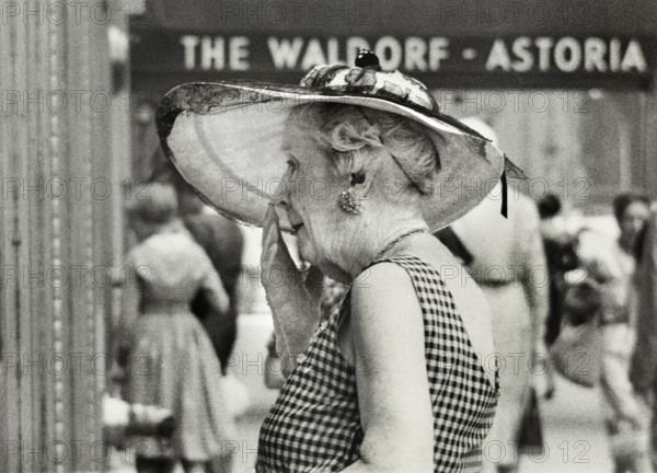 Half-length portrait of elderly woman in wide-brimmed hat standing outside Waldorf-Astoria Hotel, Manhattan, New York City, New York, USA, Angelo Rizzuto, Anthony Angel Collection, July 1959
