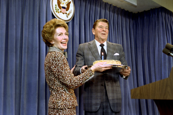 U.S. First Lady Nancy Reagan surprising U.S. President Ronald Reagan with a birthday cake during a White House press briefing, Washington, D.C., USA, President Ronald Reagan White House Photographic Office, February 4, 1983