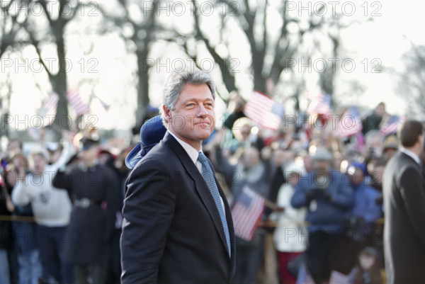U.S. President Bill Clinton and U.S. First Lady Hillary Rodham Clinton (mostly hidden with blue hat) walking along the Inaugural Parade route and waving to the crowd, Washington, D.C., USA, Bob McNeely, White House Photographer, January 20, 1993