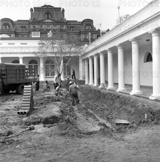 Group of unidentified workers dig into section of the lawn at the Rose Garden construction site near West Wing Colonnade, White House, Washington, D.C.., USA, Robert Knudsen, White House Photographs, April 2, 1962
